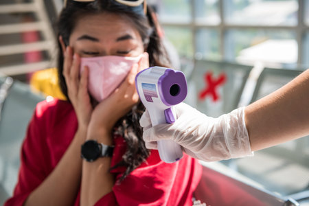 Shocked traveler with mask see high temperature result from Medical infrared thermometer on officer...