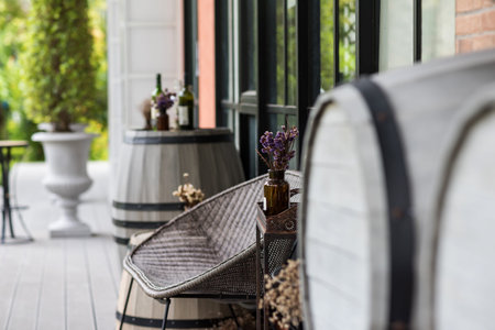 Fake flower in bottle decorated on table by chair and barrel at restaurant patio or balcony.の写真素材