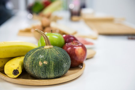 Close up fruits of banana, apple, and pumpkin on wood plate in the white clean kitchen table. Selective focusの写真素材