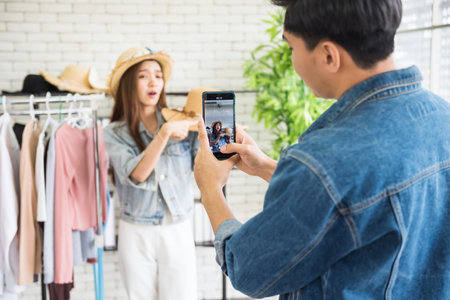 Behind the scene concept. Record live streaming by mobile or smartphone to sell hat on social media by beauty blogger. Influencer give advice about trendy fashion.の写真素材