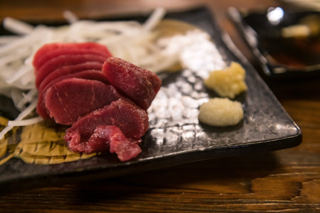Horsetail meat raw sashimi with wasabi, ginger, soy sauce on wooden tableの写真素材