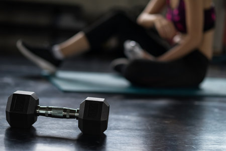 Woman break after perform training dumbbell weight exercise in fitness sport gym with copy space for text. Bodybuilding and healthy lifestyle concept.の写真素材