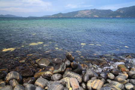 Colorful pebbles hitting by wave at beautiful rock island, called Ko Hin Ngam, at Andaman sea near Lipe island, Thailand. Famous travel destination or summer holiday maker in tropical country, Siam.の写真素材