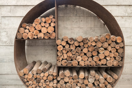Wood fired log sticks stored on rusty metal shelf attached on wooden wall.の写真素材