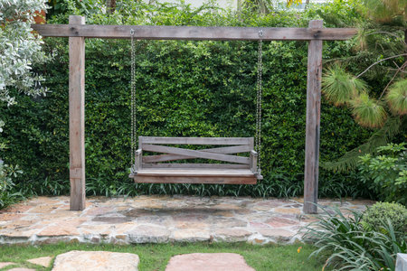 Brown wooden swing sets in outdoor park surrounded by lush green trees in cafe and restaurantの写真素材