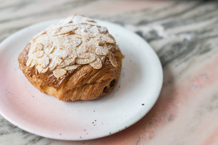 croissant sprinkled with powdered sugar and almond on marble table in cafe and restaurant.の写真素材