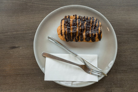 Homemade Chocolate Croissant on dish and wooden table copy space. Sweet dessert by top view.
