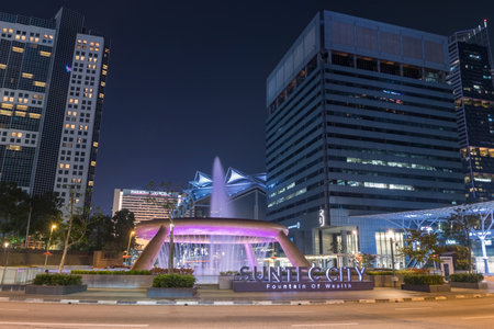 Singapore - October 15, 2023: Fountain of Wealth motion water with light up at Suntec city shopping mall against modern buildings background at night.のeditorial素材
