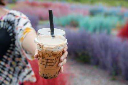 Thai milk tea with bubbles and brown sugar sauce with blur colorful grass in outdoor cafe and restaurant.の写真素材
