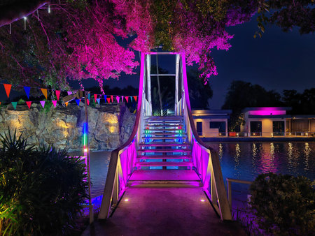 Colorful light up decoration on bridge and trees with reflection on swimming pool at night in luxury...