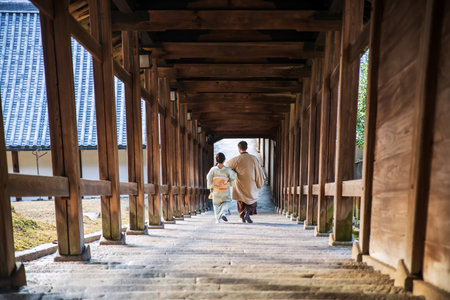 Rear couple in traditional kimono and yukata dress walk downhll staircases at wooden corridor of Todai-ji Nigatsudo temple, Nara, Japan. famous travel destination for tourist in Kansai at fall season.の写真素材