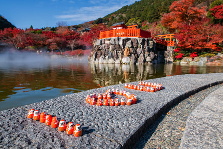 Daruma dolls by pond with steam and autumn foliage garden at Katsuo-ji temple, Minoh, Osaka, Japan. travel destination for sightseeing Kansai in fall season. Temple of victory.の写真素材