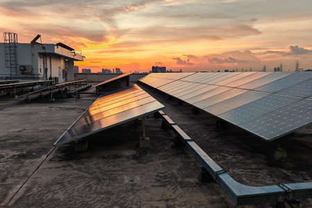 Solar panels install on roof top of office building against sunset sky at dusk, Bangkok, Thailand. Alternative power energy ecological conceptの写真素材