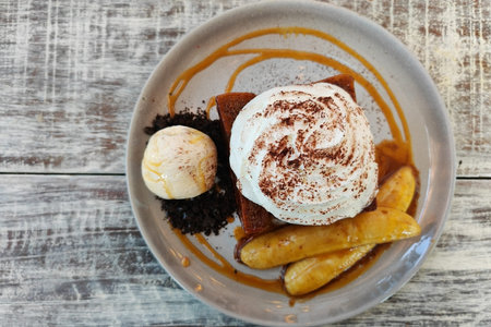 top view dessert of Honey toast and vanilla ice cream with whipping cream and banana slice on wooden...