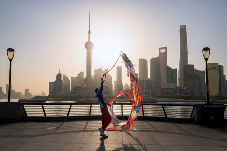 Silhouette man show ribbon dance at the Bund against pearl tower at sunrise, Shanghai. Sport and...
