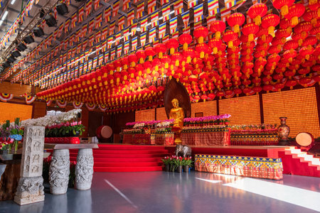 Gold Buddha statue in hall with Chinese lantern and flag decor at Longhua temple in Shanghai, China. Famous Buddhist temple of Maitreya Buddha, architectural design of Song dynasty.の写真素材