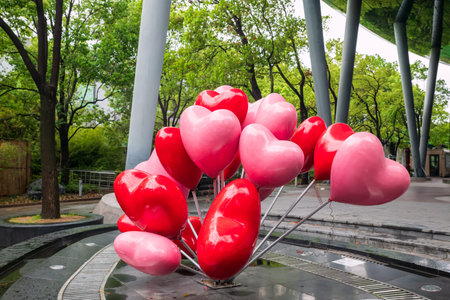 Heart shape balloons in pink and red color at front building with greenery environment at North Bund...