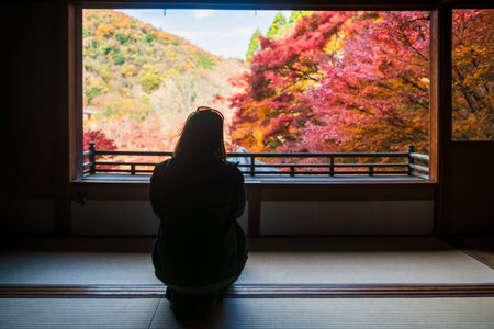 Tourist woman enjoy colorful autumn foliage leaf view from window of Rurikoin Temple upper floor,...