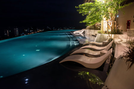 Skylounge 360 swimming pool light up on rooftop with beautiful cityscape at night of luxury hotel.