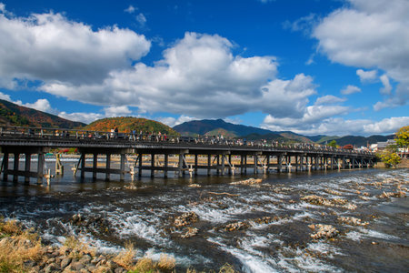 People in Togetsukyo bridge with autumn color against blue sky in Arashiyama, Kyoto, Japan. Famous travel destination in Kansai especially on Fall and spring season.の写真素材