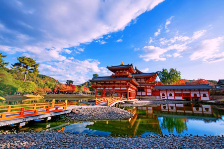 Phoenix Hall of Byodo-In temple with colorful maple leaves and skyline reflection in autumn, Uji,...