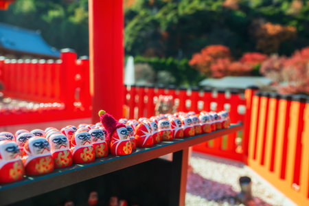 Cute daruma dolls with red scarf hat at Katsuo-ji temple shrine with autumn leaf colors, Minoh, Osaka, Japan. Famous travel destination for sightseeing Kansai in fall season. Temple of victory.の写真素材