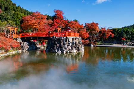 Torii gate to shrine by pond with steam and autumn leaf garden against blue sky at Katsuo-ji temple, Minoh, Osaka, Japan. Famous travel destination for sightseeing Kansai in fall. Temple of victoryの写真素材