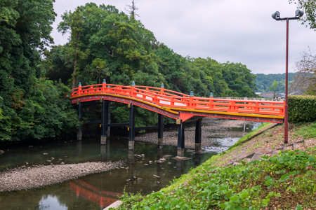 Red curve arching bridge over green pond and Japanese garden at entrance of Usa shrine in Oita prefecture, Kyushu, Japan. Famous travel destination for sightseeing.の写真素材