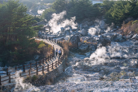 people walk on Hell valley Jigoku footpath at Mount Unzen onsen hot springs at sunset by Shimabara, Nagasaki, Kyushu, Japan. Hot water, sulfur gases and steam spout out volcanic spring field.の写真素材
