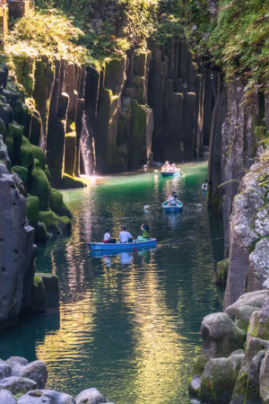 Tourist people sailing rowboat over green water through canyon of Takachiho gorge, Nishiusuki, Miyazaki, Kyushu, Japan. Famous travel destination of volcanic gorge to view Nature Scenery.の写真素材