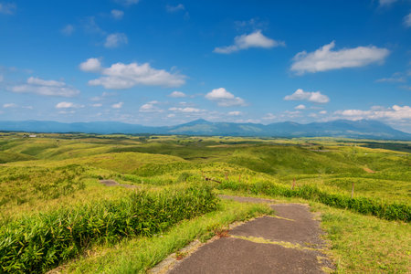Daikanbo observatory viewpoint walking trail with green grasses on hill and blue sky, Mount Aso, Kumamoto, Japan. Famous travel destination to sightseeing Kyushu.の写真素材