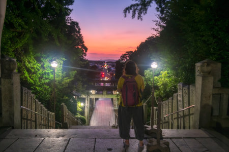Tourist people view torii gate and city from Miyajidake Shrine temple at dusk with twilight sky, Fukutsu, Fukuoka, Japan. Famous travel destination to sightseeing Kyushu in autumn or fall.の写真素材