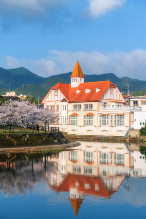 Vertical view of Siebold no Yu and sakura cherry blossom with skyline reflect on river at Ureshino onsen park, Saga, Japan. Famous travel destination for spa area with hot springs in springtime.の写真素材