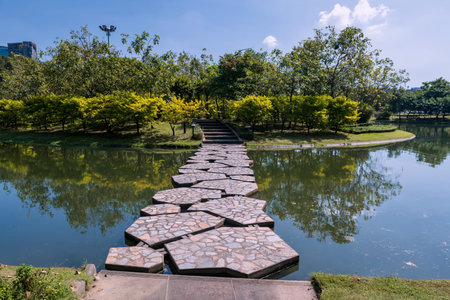 bridge across pond with skyline reflection on water at Wachirabenjathat park against blue sky,...