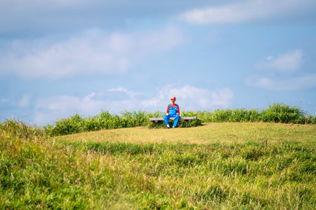 Kumamoto, Japan - Oct 13, 2025: Japanese man in costume sit on mountain summit at Daikanbo observatory against blue sky.の写真素材