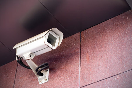 Office building with white security camera under a ceiling