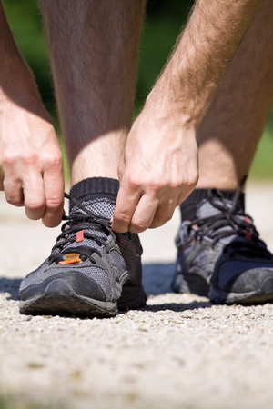 Trail runner in summer nature tying sport shoes