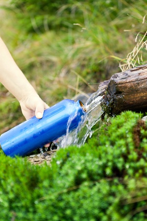 Woman filling water bottle from stream on hiking tripの写真素材