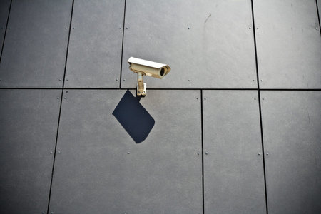 Security camera on gray modern building wall, technology in cityの写真素材