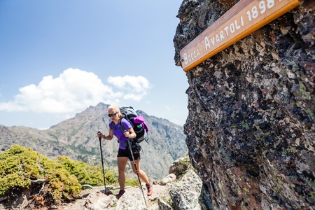 Woman hiking with backpack in mountains, Bocca Avartoli 1898m above see level. Trekking in high mountains and reaching a pass. Selective focus on sign.の写真素材