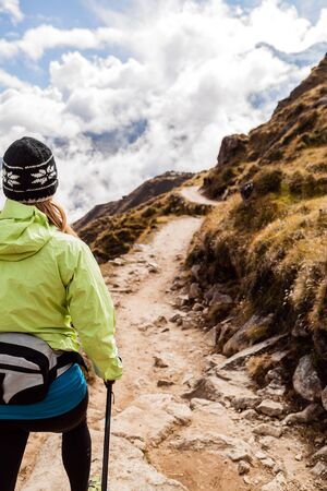Young woman hiker hiking in Himalaya Mountains in Nepal. Nordic walking, sport and fitness in autumn nature outdoors, beautiful landscapeの写真素材