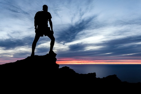 Male silhouette hiker with backpack on top of mountain looking at beautiful night landscape の写真素材