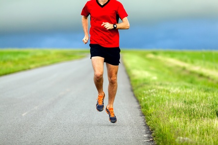 Man runner running on country road on summer sunsetの写真素材