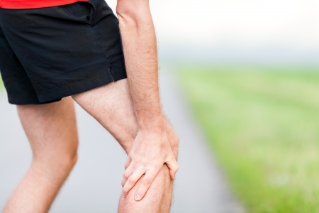 Runner leg and muscle pain during running training outdoors in summer natureの写真素材