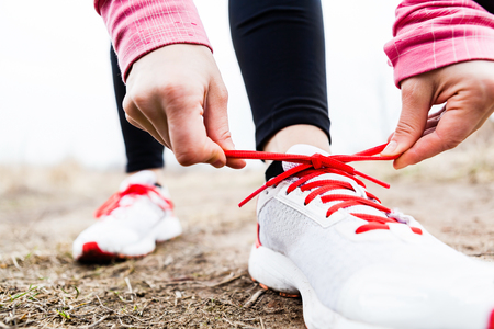 Woman runner tying sport shoes. Walking or running legs, autumn adventure and exercising outdoors.の写真素材