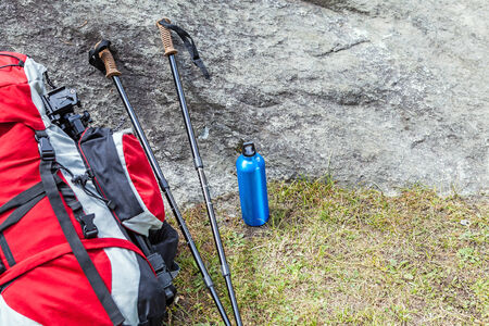 Hiking equipment in mountains, sticks, water bottle and backpack on a rockの写真素材