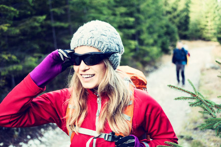 Man and woman hikers trekking on trail in mountains winter or autumn. Vintage analog photography of young couple walking on country road in forest. Holidays weekend in Tatras, Poland.の写真素材