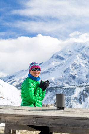 Young woman hiker drink coffee or tea in beautiful Himalaya mountains on hiking trip base camp, Nepal. Active person resting outdoors in winter white nature. Female backpacker camping outside recreation activeの写真素材