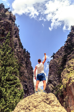 Happy climber hiker or trail cross country runner reaching life goals at summit success man business concept. Young runner up arms outstretched freedom and happiness rock climbing achievement in mountainsの写真素材
