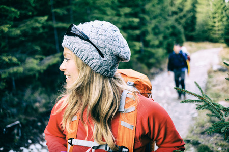 Man and woman hikers walking with backpacks on trail in green forest mountains. Young couple camping and trekking on country road, healthy lifestyle in beautiful inspirational landscape. Weekend vacations in Tatra Mountains, Poland.の写真素材